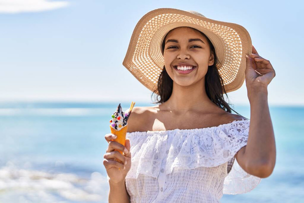 Young african american woman tourist smiling confident eating ice cream at seaside - Photo, image