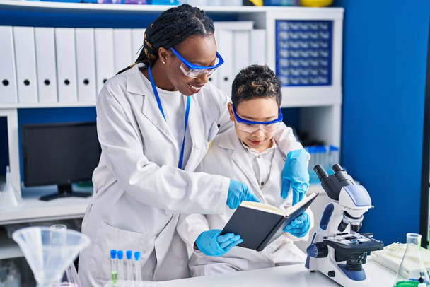 Afroamericanos madre e hijo científicos sonriendo confiados de pie juntos laboratorio - Foto, imagen