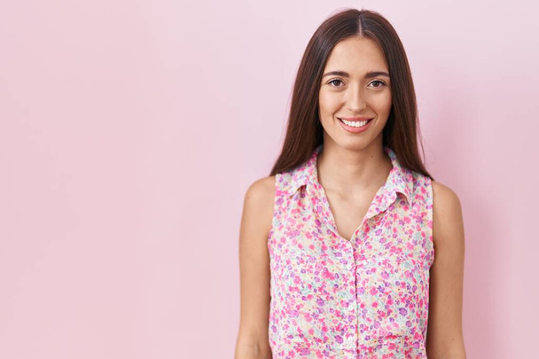 Young hispanic woman with long hair standing over pink background with a happy and cool smile on face. lucky person.  - Foto, immagini