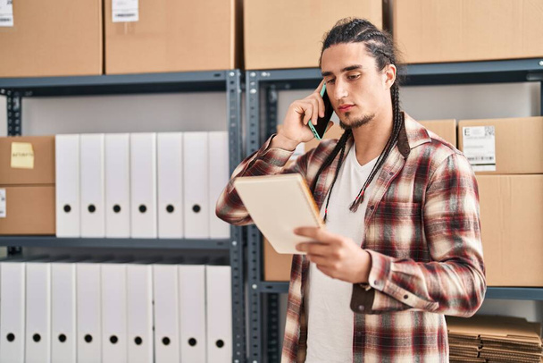 Молодий чоловік електронної комерції бізнесмен розмовляє на смартфоні читаючи блокнот в офісі
 - Фото, зображення