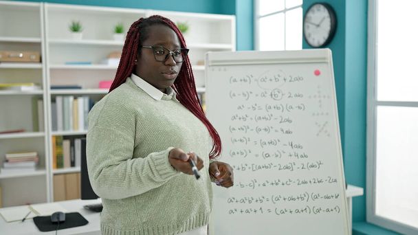 Örgü örmüş saç öğretmeni olan Afrikalı kadın üniversite kütüphanesinde matematik dersi veriyor. - Fotoğraf, Görsel