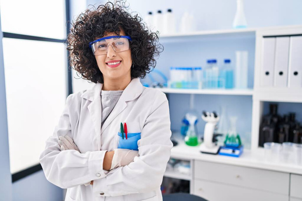 Young middle east woman scientist standing with arms crossed gesture at laboratory - Foto, afbeelding