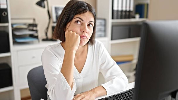 オフィスでコンピュータ思考を使用して若い美しいヒスパニック系女性のビジネスワーカー - 写真・画像