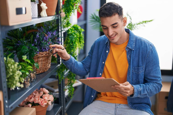 Young hispanic man florist smiling confident writing on document at florist store - Photo, Image