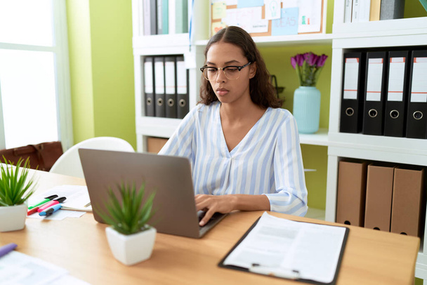 Ofiste çalışan genç Afro-Amerikan iş kadını laptopu kullanıyor. - Fotoğraf, Görsel