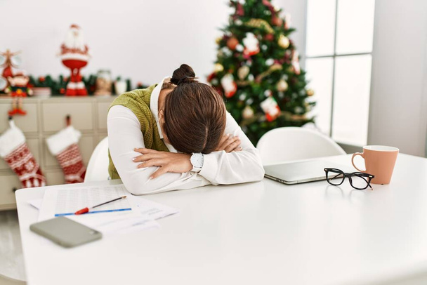 Mladá krásná hispánská žena sedí u vánočního stromku pracuje ve stresu doma - Fotografie, Obrázek