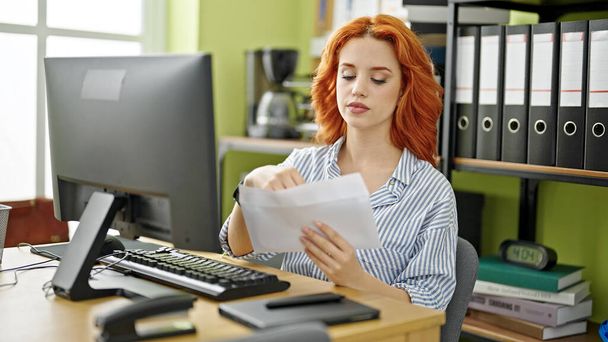 Jonge roodharige vrouw zakenman met behulp van computer openen envelop brief op kantoor - Foto, afbeelding