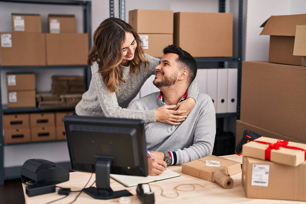 Man and woman ecommerce business workers hugging each other working at office - Foto, Bild