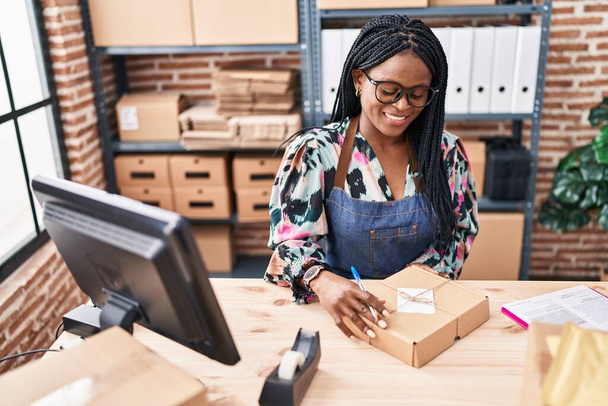 Femme afro-américaine commerce électronique travailleur d'entreprise tenant paquet au bureau - Photo, image