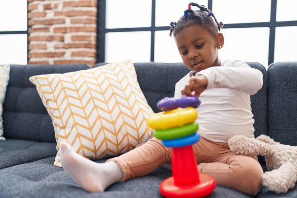 African american girl playing with hoops game sitting on sofa at home - Fotó, kép