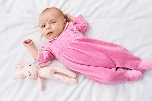 Imádnivaló spanyol baba fekszik az ágyon játékkal a hálószobában - Fotó, kép