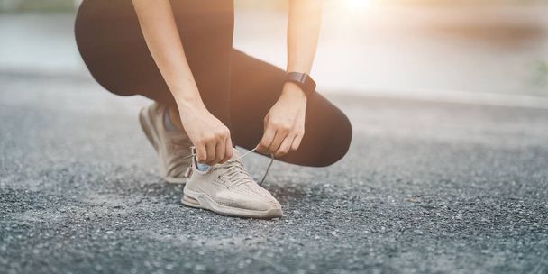 Donna asiatica sana è riscaldare prima di fare jogging e allacciare i lacci delle scarpe all'aperto. Una ragazza in forma che corre. Esercizio femminile al parco all'aperto. - Foto, immagini