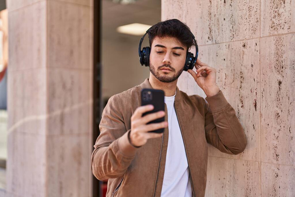 Fiatal spanyol férfi zenét hallgat az utcán. - Fotó, kép