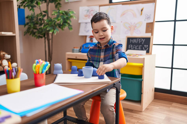 Чарівний іспаномовний хлопчик грає з іграшками, сидячи на столі в дитячому саду - Фото, зображення