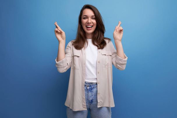 active 30s dark-haired woman in a beige shirt on a blue background. - Photo, Image