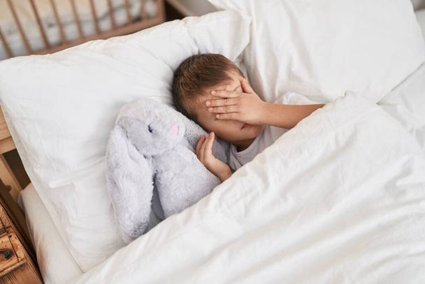 Adorabile caucasico ragazzo stressato sdraiato sul letto con bambola in camera da letto - Foto, immagini