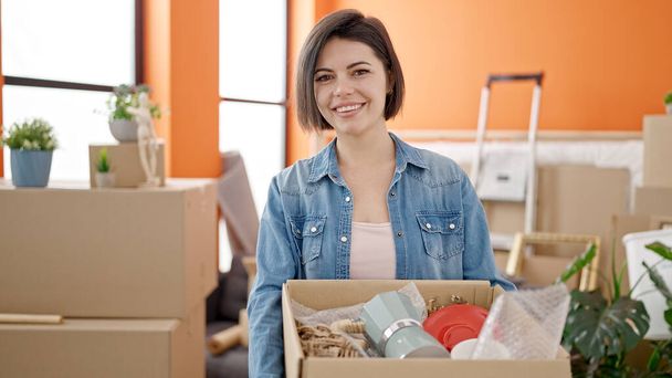Young caucasian woman smiling confident holding package at new home - Photo, Image