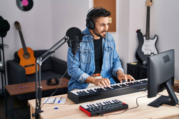 Fiatal spanyol férfi zeneszerző zenét komponál a zenei stúdióban - Fotó, kép