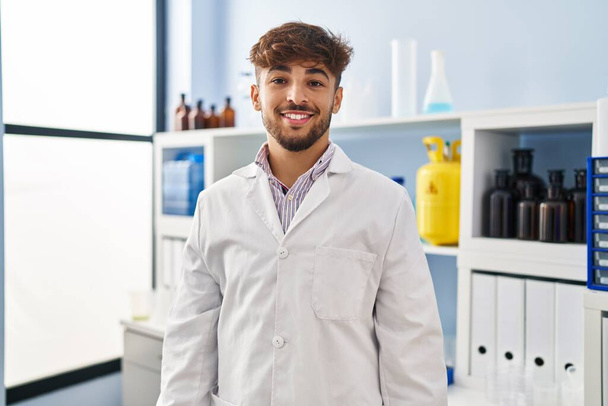 Араб с бородой работает в научной лаборатории со счастливой и прохладной улыбкой на лице. счастливчик.  - Фото, изображение