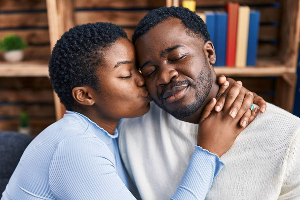 man en vrouw paar knuffelen elkaar zitten op bank thuis - Foto, afbeelding