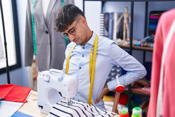 Молодой латиноамериканец стресс с помощью швейной машинки в портной мастерской - Фото, изображение