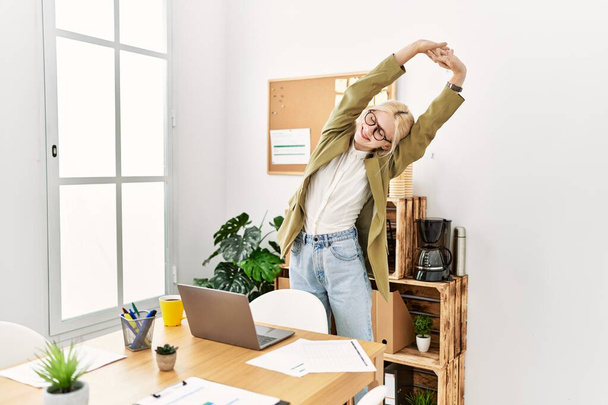 jong blond vrouw zakenman stretching terug staan op kantoor - Foto, afbeelding