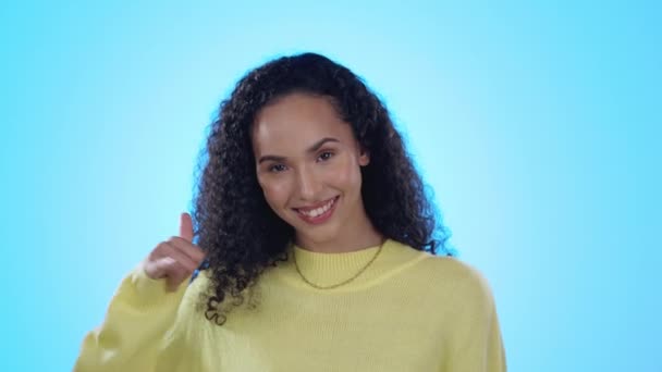 Flirting, happy and woman with a call me gesture in a studio with a wink and positive mindset. Happiness, smile and portrait of a young female model with a phone hand sign isolated by blue background. - Footage, Video
