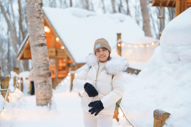 Женщина турист Посещение в Фурано, путешественник в свитер осмотр достопримечательностей Ningle Terrace коттеджей со снегом зимой. ориентир и популярны для достопримечательностей на Хоккайдо, Япония. Концепция путешествий и отдыха - Фото, изображение