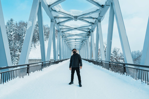 男の観光客美瑛を訪れる、気象観光の旅行者冬は雪と白ひげの滝の橋。北海道の観光スポットとして人気のランドマーク。旅行と休暇のコンセプト - 写真・画像