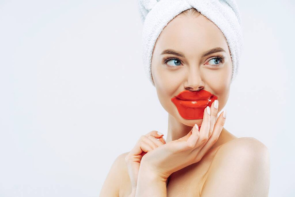 Belle femme porte un masque hydrogel pour les lèvres, une peau lisse, un maquillage minimal, essaie un nouveau cosmétique. - Photo, image