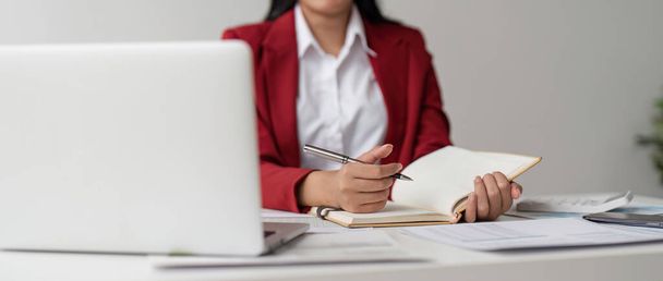 Las mujeres de negocios trabajan en computadoras y escriben en bloc de notas con bolígrafo para calcular los estados financieros de la oficina. - Foto, Imagen