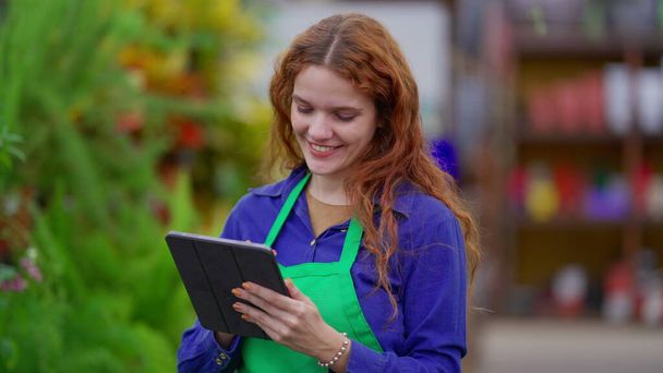 Inventory Assessment by Female Manager in Vibrant Plant Store. Tech-Savvy Young Woman Optimizing Business Shop Operations - Foto, Imagen