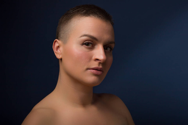 portrait of young woman with short hair and bare shoulder, on blue background - Foto, Imagem
