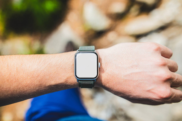 A smartwatch on a guy's wrist with an empty screen on a mountain trail - template for fitness or other applications. - Foto, Imagem