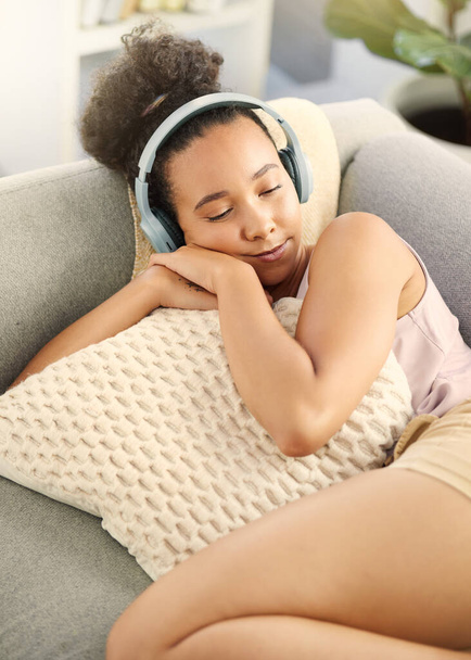 Sleeping, music headphones and woman on sofa in home living room for streaming. Meditation, couch and African person listening to radio, audio or podcast, jazz and sound for calm, peace and relax - Foto, Bild