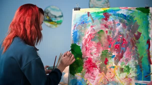 хобі, творча художниця-жіночка з використанням пензлів і фарб малює творчу картину в приміщенні - Кадри, відео