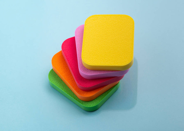 Heap of colorful cosmetic sponges on blue background. Top view - Photo, Image