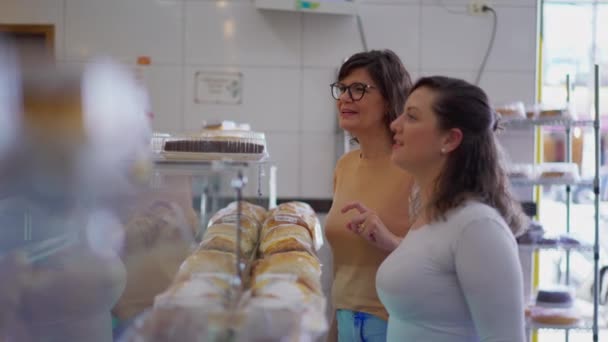 カフェテリアデリで食べ物を探している2人の女性客。商品を見ているカウンターの女性,食料品店 - 映像、動画
