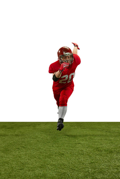 Front view dynamic image of man, american football player in red uniform running on field during game against white background. Professional sport, action, lifestyle, competition, training, ad concept - 写真・画像