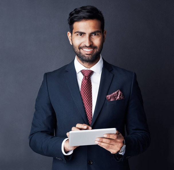 Businessman, tablet and smile in studio, dark background or research stock market trading news online. Corporate trader, indian man or digital technology for investment management, finance or website. - Photo, image