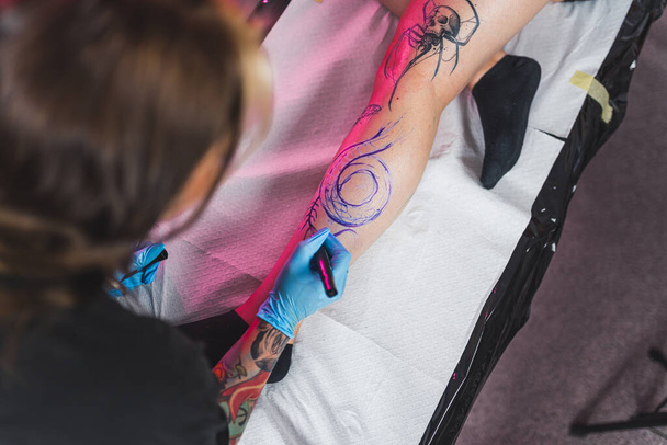 Szabadkézi technika - tetoválás mester rajz marker egy test, nagy szögű lövés. Kiváló minőségű fénykép - Fotó, kép