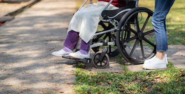 Дом престарелых. Молодой сиделка помогает пожилой женщине в инвалидном кресле - Фото, изображение