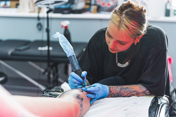средний снимок молодого мастера татуировки, рисующего новую татуировку с удовольствием, концепция татуировщика. Высокое качество фото - Фото, изображение