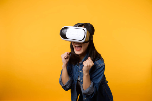 Aasian nuori nainen saada kokemusta yllään virtuaalitodellisuus kuulokkeet peli viihdettä eristetty keltaisella pohjalla. Cyber Future videopelikonseptin voittaja. - Valokuva, kuva