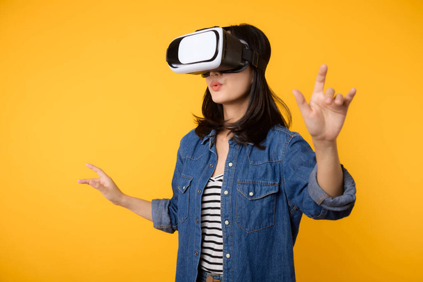 Asijské mladá žena získat zkušenosti s nošením virtuální realita sluchátka hra zábava izolované na žlutém pozadí. Vítěz konceptu kybernetické budoucnosti videoher. - Fotografie, Obrázek