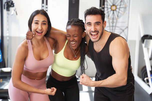 Gruppe von Fitness-Freunden beugt den Arm sehr glücklich und lächelt in der Turnhalle - Foto, Bild