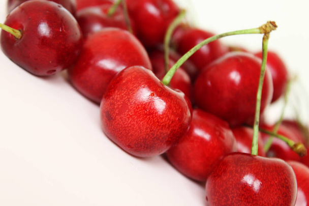  cherries isolated close up. Healthy food fruit red cherries on a light pink background - Foto, afbeelding