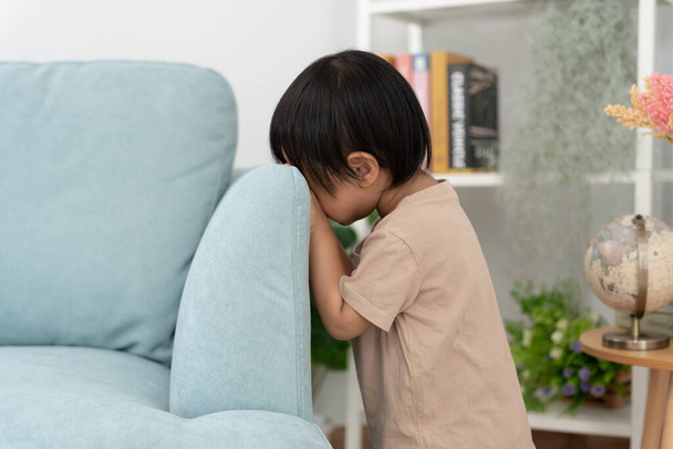 little asian children kid girl covering his eyes with hands, playing hide and seek standing next a wall house, Adorable child having fun in the home. happy family have fun with kids, activity, learning - Zdjęcie, obraz