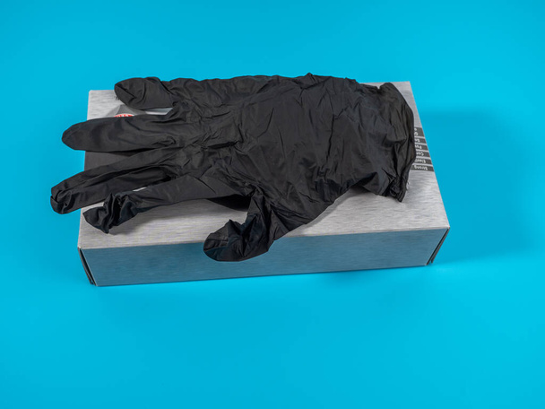 Gants noirs jetables isolés sur un fond bleu. Pack de gants jetables noirs. - Photo, image