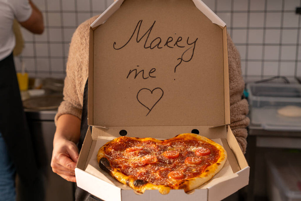 Una romántica propuesta de amor con deliciosa pizza y la inscripción en la caja de Merry Me. Foto de alta calidad - Foto, imagen